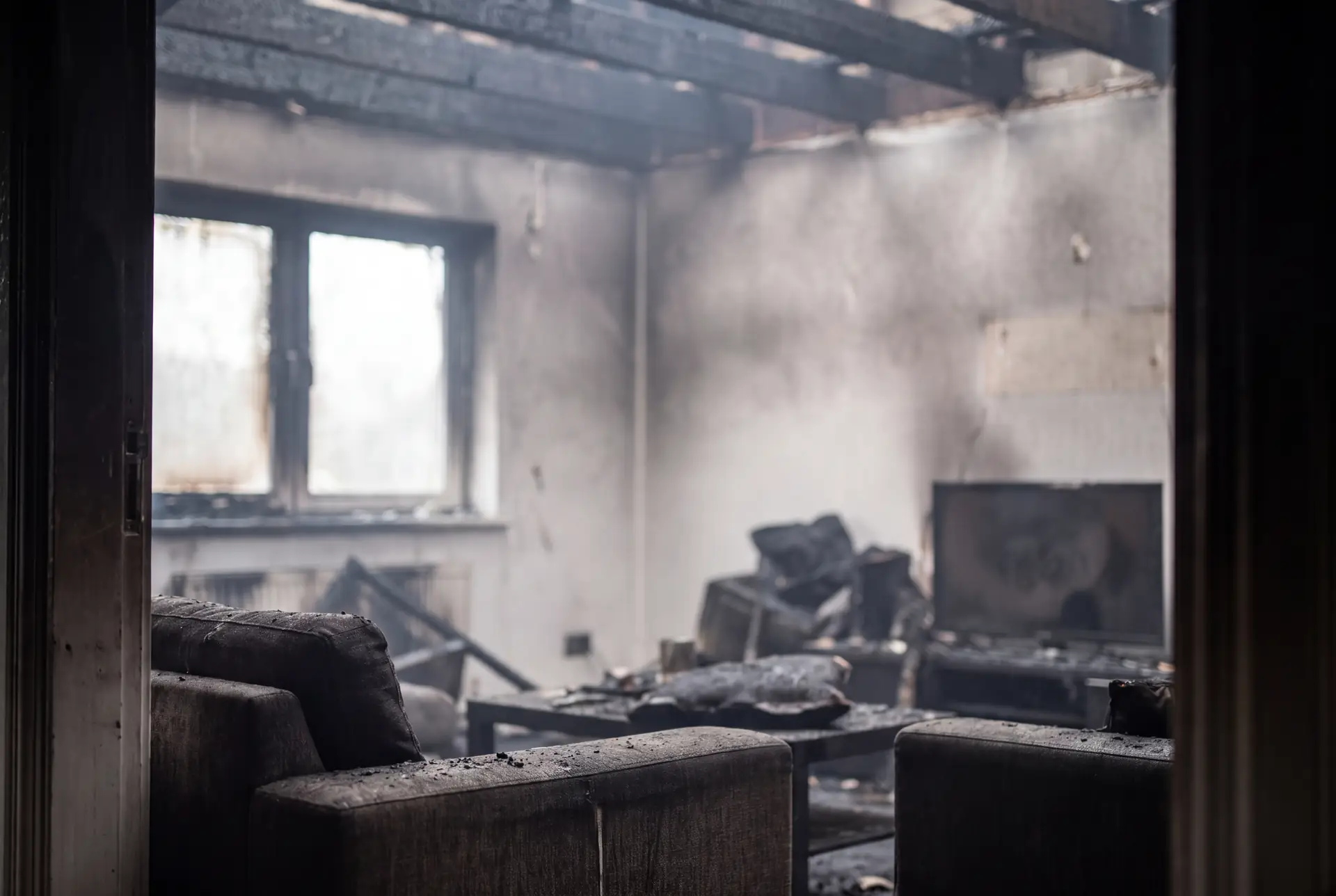 Fire and smoke damage inside a home, with soot on the walls and furniture